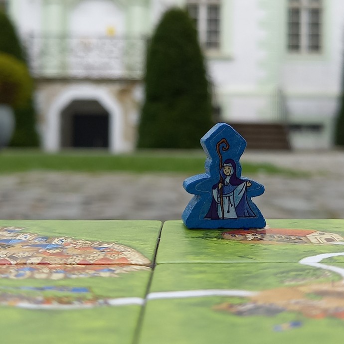 Spielfigur des Legespiels Carcassonne. Im Hintergrund sieht man den Haupteingang der Abtei Liesborn. (vergrößerte Bildansicht wird geöffnet)