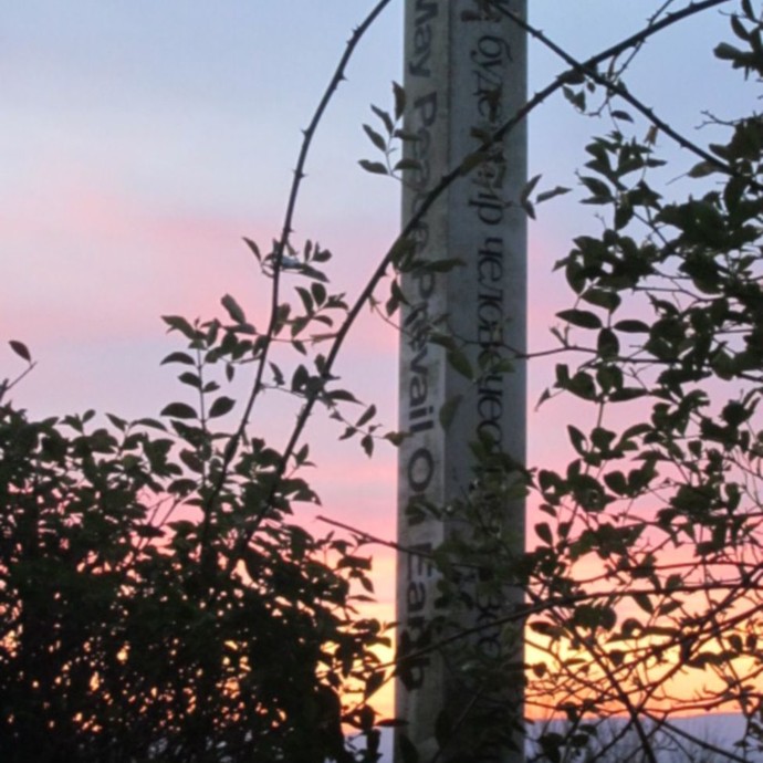 Säule bei Sonnenuntergang mit Inschrift „May Peace Prevail On Earth“ („Möge Frieden sich auf Erden durchsetzen“). © Manuela Baumann.