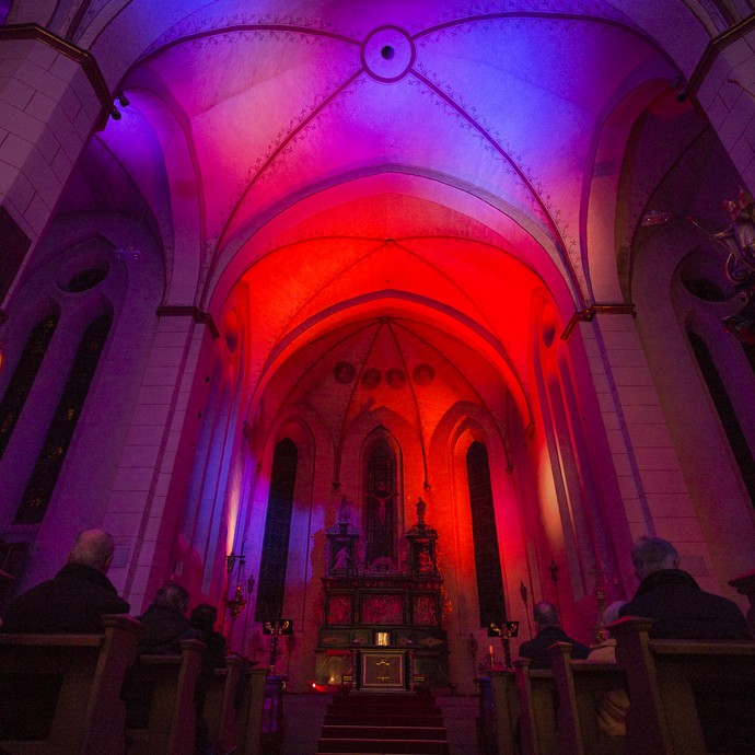 Rot und blau erleuchteter Innenraum der Kirche des ehemaligen Klosters Wedinghausen. © LWL, Fotografie Sarah Bömer.